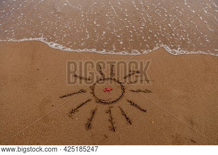 Symbol Of The Sun And A Plane By The Sea. Painted Sun On The Sand, Sea Coast, Figure Of A Red Plane,