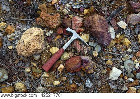 Steel Geologist Rock Pick Over Colorful Red And Yellow Rocks In Mining Area Rich With Copper Ore And