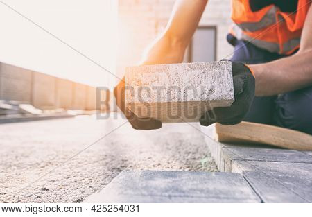 Worker lining paving slabs path