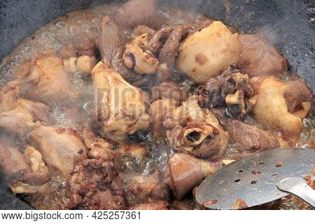 Large Pieces Of Lamb Meat With Lamb Fat Dumba Close-up Fried In Oil With Bubbles In A Black Cauldron