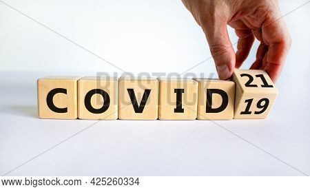 Symbol Of Covid-19 Pandemic In 2021 Year. Businessman Turns The Wooden Cube And Changes Words 'covid