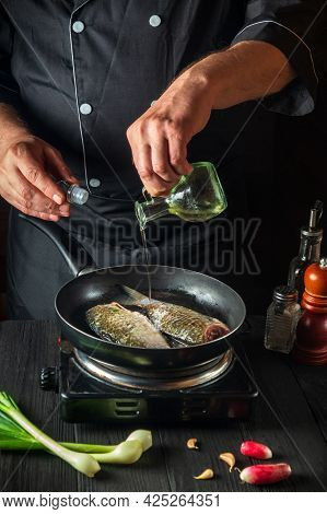 The Chef Prepares Fresh Fish In A Pan With Oil. Preparation For Cooking Fish Food. Working Environme