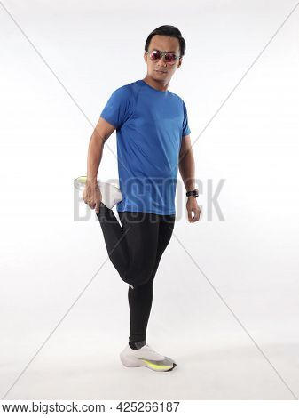 Asian Male Runner Warming Up Prepararing His Body Before Running Workout. Stretch His Leg Muscle, St