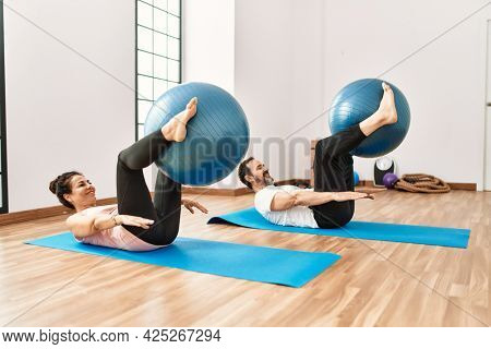Mature hispanic couple doing excersice and stretching at yoga room. Two adult people doing pilates and flexibility workout