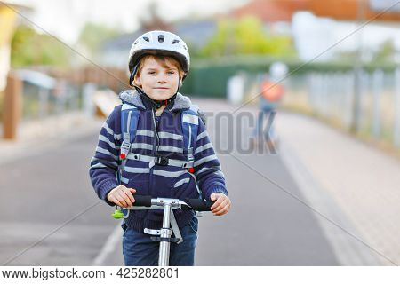 Active School Kid Boy In Safety Helmet Riding With His Scooter In The City With Backpack On Sunny Da