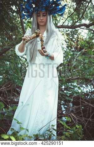 Beautiful Girl In Wreath Of Flowers In Forest. Portrait Of Young Beautiful Woman Wearing White Bride