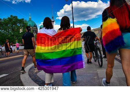 Berlin, Germany - June 26, 2021 - Two Women Share A Rainbow Flag On Christopher Street Day (csd), In