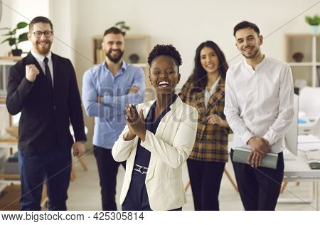 Happy Business Leader Clapping Hands Standing In Office With Team Of Her Employees