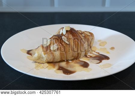 Baked Croissant With Caramel And Syrup On White Plate For Homemade Breakfast With Almond