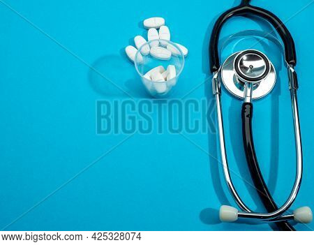 Pills And Stethoscope On A Blue Background. The Stethoscope Lies On A Blue Background.