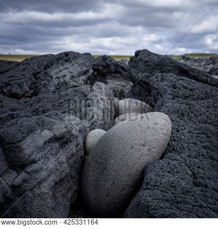 Lava Stones Fitted In A Fissure In A Big Lava Rock, Blurred Cloudy Background, Hvaleyri Beach, Icela