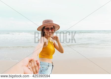 Asian Woman Holding Boyfriend Hand And Running On Tropical Beach To The Sea On A Holiday. An Excited