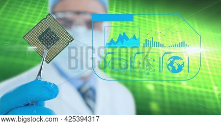 Medical icons over male doctor wearing face mask holding computer chip against green background. medical research and science technology concept