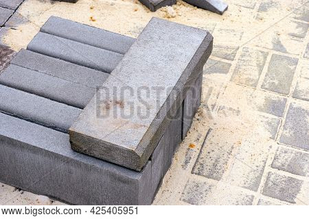 Stack Of Curbstones On A Stone Tiles In Sand.