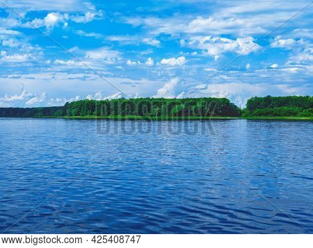 The Beautiful And Peaceful View On The Lake And The White Clouds In The Blue Sky. The Spring Or Summ