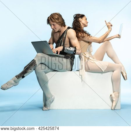 Tablet, Laptop, Digital. Young Couple Of Ballet Dancers In Ancient Rome Costums At Blue Studio.