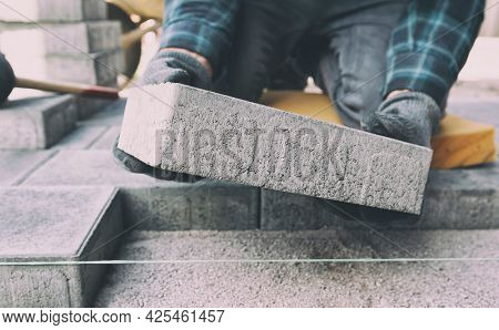 Worker lining paving slabs path