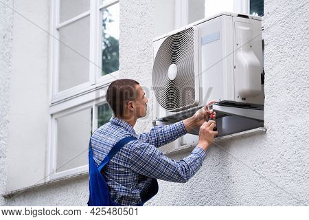 Technician Cleaning And Repairing Air Condition Appliance. Ac Unit Maintenance