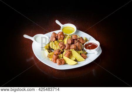 Salchipapa, Peruvian Grilled And Sliced Fresh Pork Sausage, Potato Fry On Black Background.
