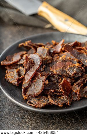 Sliced beef jerky. Dried beef meat on plate on old kitchen table.
