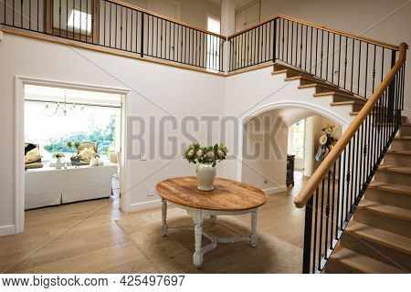 General view of house interior with table and vase with flowers in spacious hallway and staircase. modern interiors and house decoration concept.