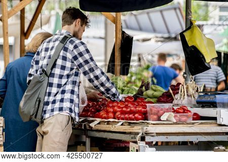 Young Pesron Choose Fresh Ripe Veggies At The Outdoor Market And Purchasing It