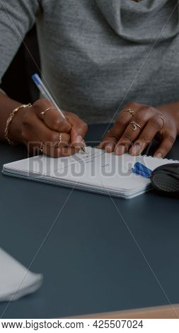 Closeup Of Student With Black Skin Writing Communication Homework On Notebook While Sitting At Desk 