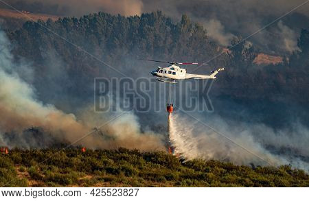Helicopter With Bambi Bucket Throwing Water To Flames