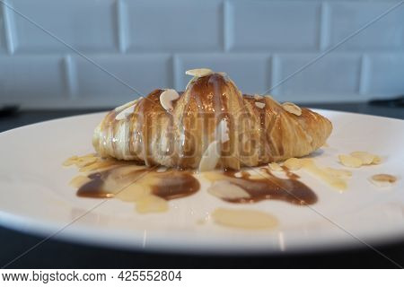 Baked Croissant With Caramel And Syrup On White Plate For Homemade Breakfast With Almond