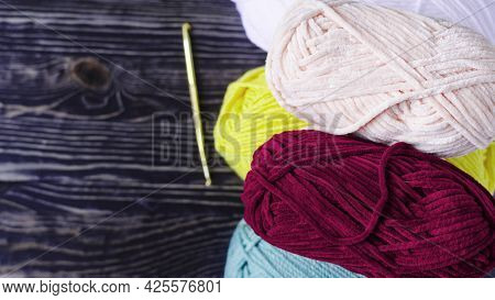 Balls Of Colored Yarn And A Knitting Hook On The Background Of A Dark Copy Space Tree. The Concept O