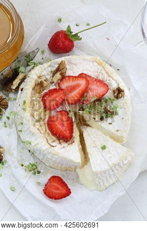 Camembert With Strawberries, Nuts And Honey On A White Plate