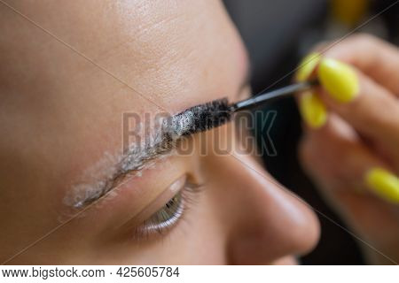 Beautician Making Depilation With Wax Strip Young Womans Eyebrows In Spa Center. Attractive Woman Ge