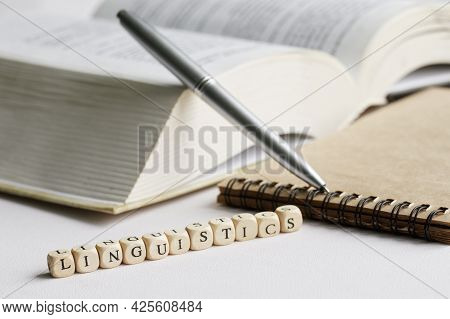 The Word Linguistics Next To An Open Book, Notepad And Pen. The Concept Of Studying The Humanities I