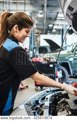 Young female mechanic wiping the engine oil dipstick