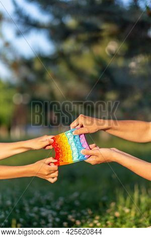 Children's Hands Pull The Eternal Pupyrka In Different Directions Against The Background Of Nature. 