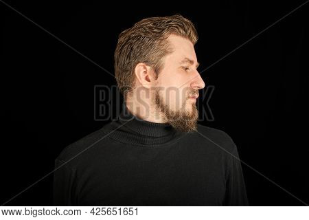 Cute Bearded Man, Half-face Portrait, Black Background. Young Guy In Black Polo Neck Sweater. Confid