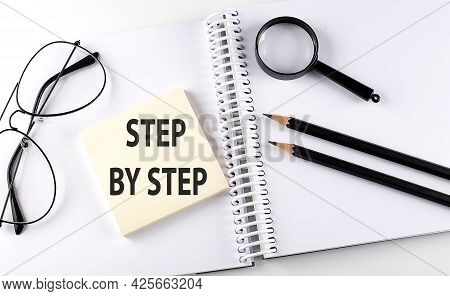Word Step By Step On The Sicker On The Notebook With Pencils,magnifier And Glasses