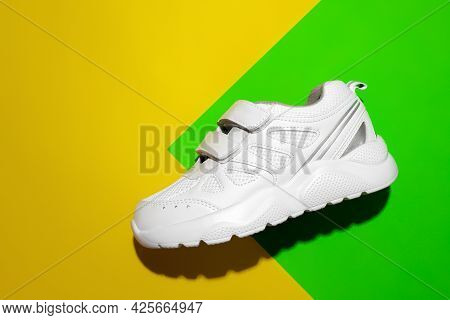 Top View One White Childrens Sneakers With Velcro Fasteners On A Geometric Paper Lime Background Wit