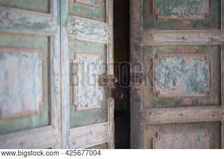 Old Paint Faded Wooden Door Half Open With Lock In Focus. Phongsali, Laos.