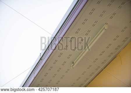 Low Angle View Of Roof Eaves And Neon Soffit At The Ceiling With Sky Background