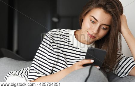 Portrait Of Relaxed Young Woman Resting At Home With Smartphone. Girl Sitting Comfortable On Sofa, L