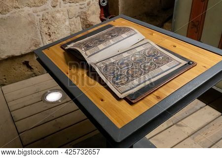 Acre, Israel, June 26, 2021 : Stylization Of An Open Old Book With Old Drawings And Old Text Lying O