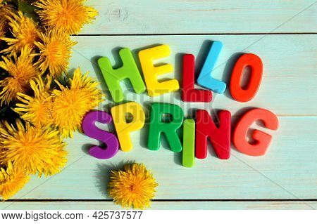 On A Wooden Background There Is An Inscription In Multi-colored Letters Hello Spring Surrounded By D