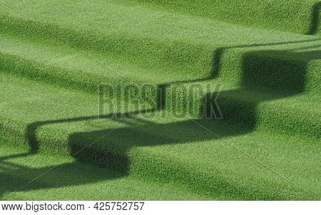 Side View Of Artificial Grass On Outside Stairs In Front Yard Area With Sunlight And Shadow On Surfa