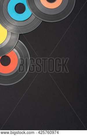 Multi Colored 7 Inch Single Vinyl Records On A Black Background With Empty Space For Text. Top Down 
