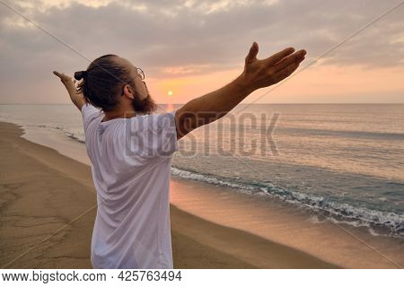 Man Doing Surya Namaskar Or Salute To The Sun Or Sun Salutation. Man Practices Yoga At Sea Beach Dur