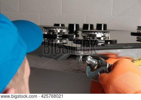 Serviceman Installs  Gas Hob In  Kitchen, Connecting  Gas Hose