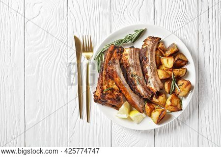 Grilled Pork Ribs Served With Roast New Potatoes On A White Plate On A Wooden Table, Horizontal View