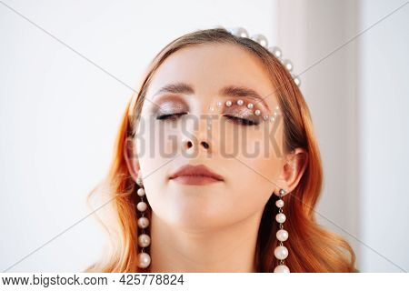 Close-up Portrait Of A Pale-skinned And Red-haired Caucasian Woman With Closed Eyes With Makeup Made