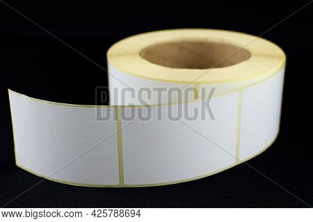 Babina Of Self-adhesive Stickers On A Black Background. Self-adhesive White Label Roller For Printin
